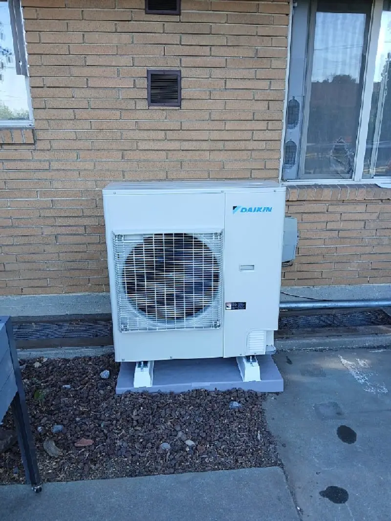 Daikin heat pump installed on a pad beside a brick Wenatchee home by Central Washington Heating and Air