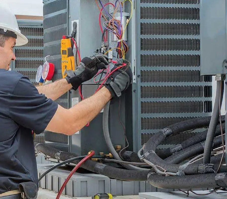 Central Washington Heating and Air technician testing a commercial HVAC unit with a multimeter